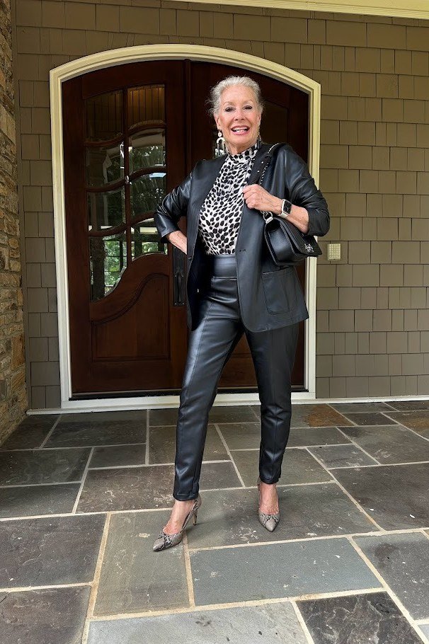 Black moto jacket over leopard top, black faux-leather leggings, heels, leggings outfit idea for women over 50