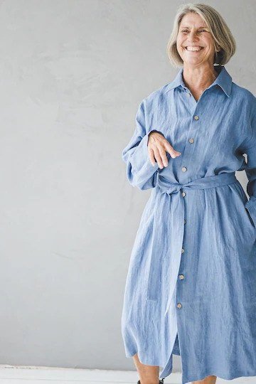 linen summer dresses for women over 60: older woman in chambray blue belted shirt dress in bright studio
