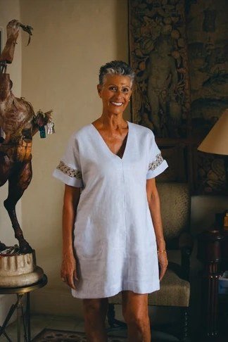 linen summer dresses for women over 60: older woman in white v-neck linen shift dress on older woman with short gray hair in studio