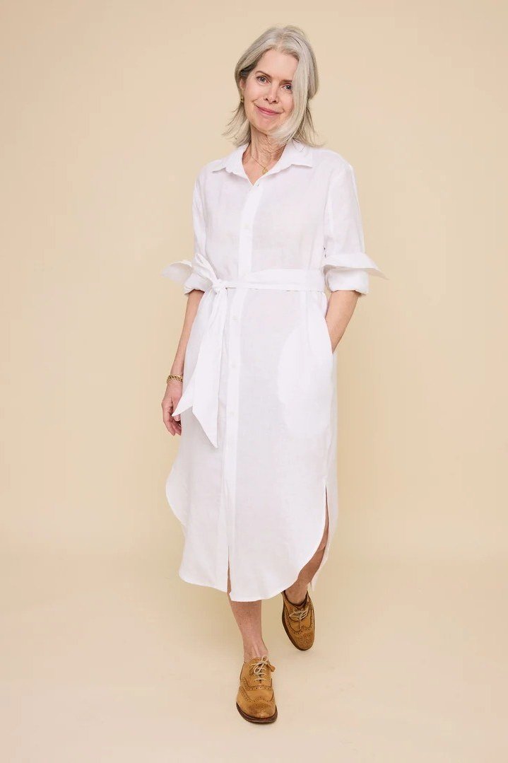 linen summer dresses for women over 60: older woman in white tie-waist linen shirt dress midi in studio