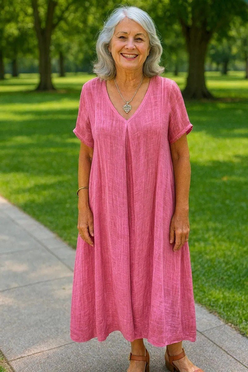 linen summer dresses for women over 60: older woman in hot pink v-neck linen midi dress in green park