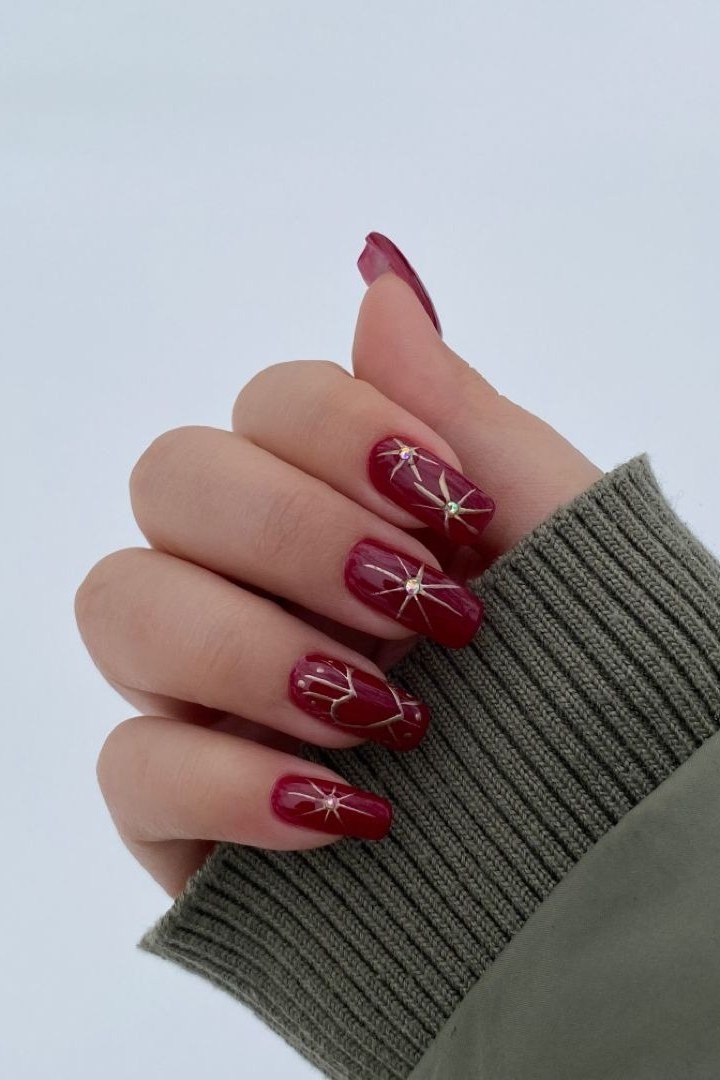 Wine red with white starburst accents nails for women over 50 - classy winter nail idea 4
