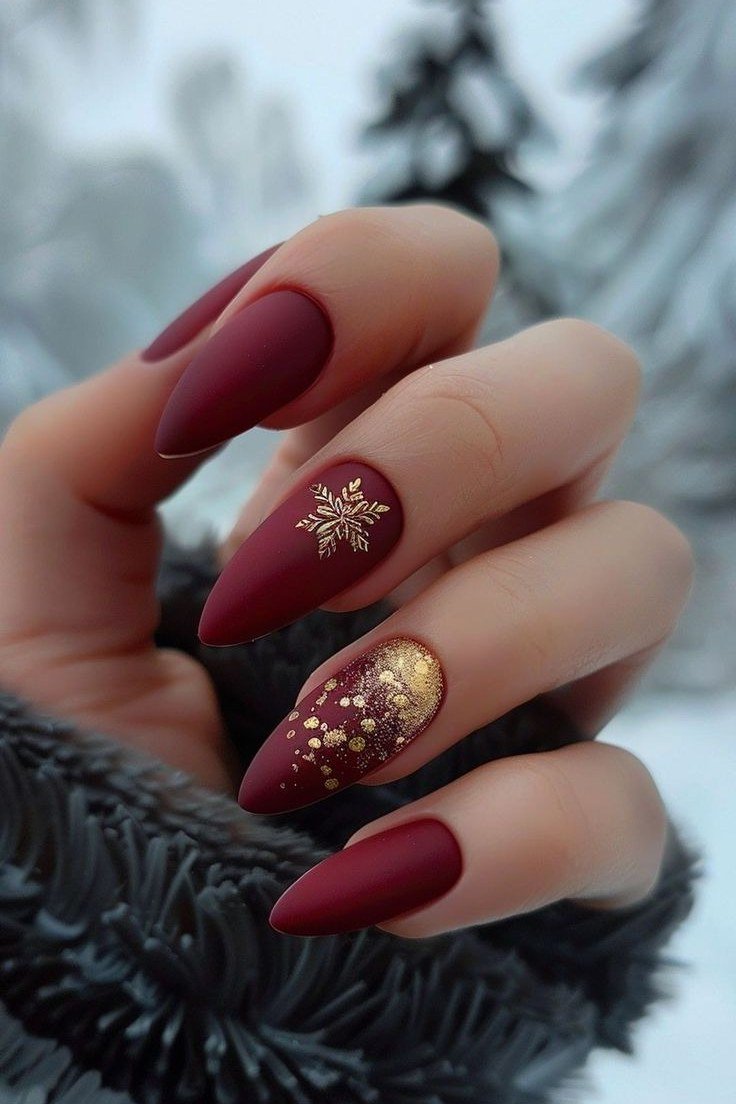 Matte burgundy almond with gold snowflakes nails for women over 50 - classy winter nail idea 7