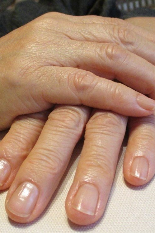 Glossy nude nails with hands stacked - simple natural nail idea for women over 60