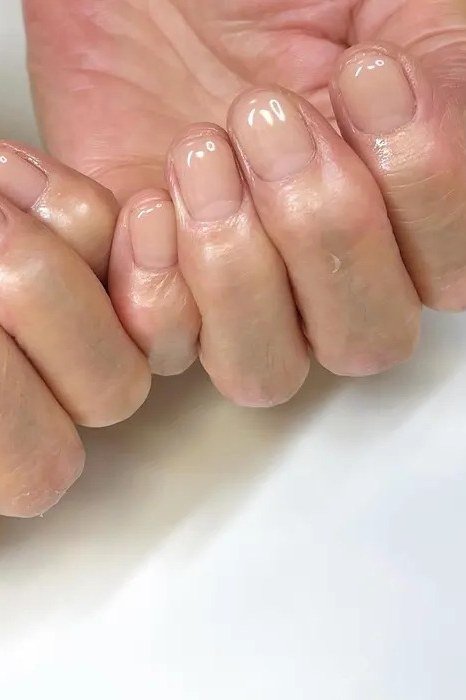Glossy natural nails with fingers of two hands touching - simple natural nail idea for women over 60