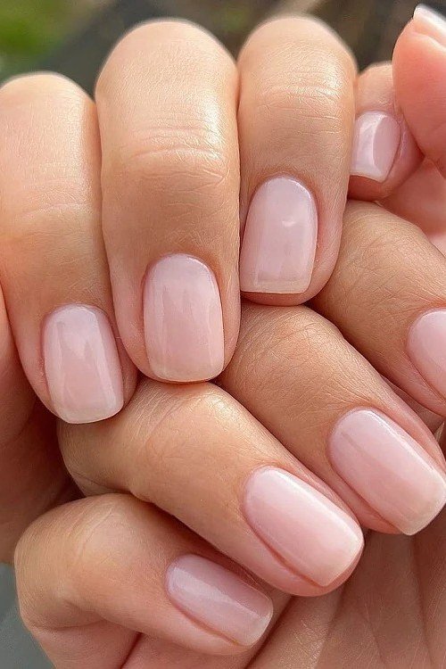 Milky pink nails on mature hands clasped together - simple natural nail idea for women over 60