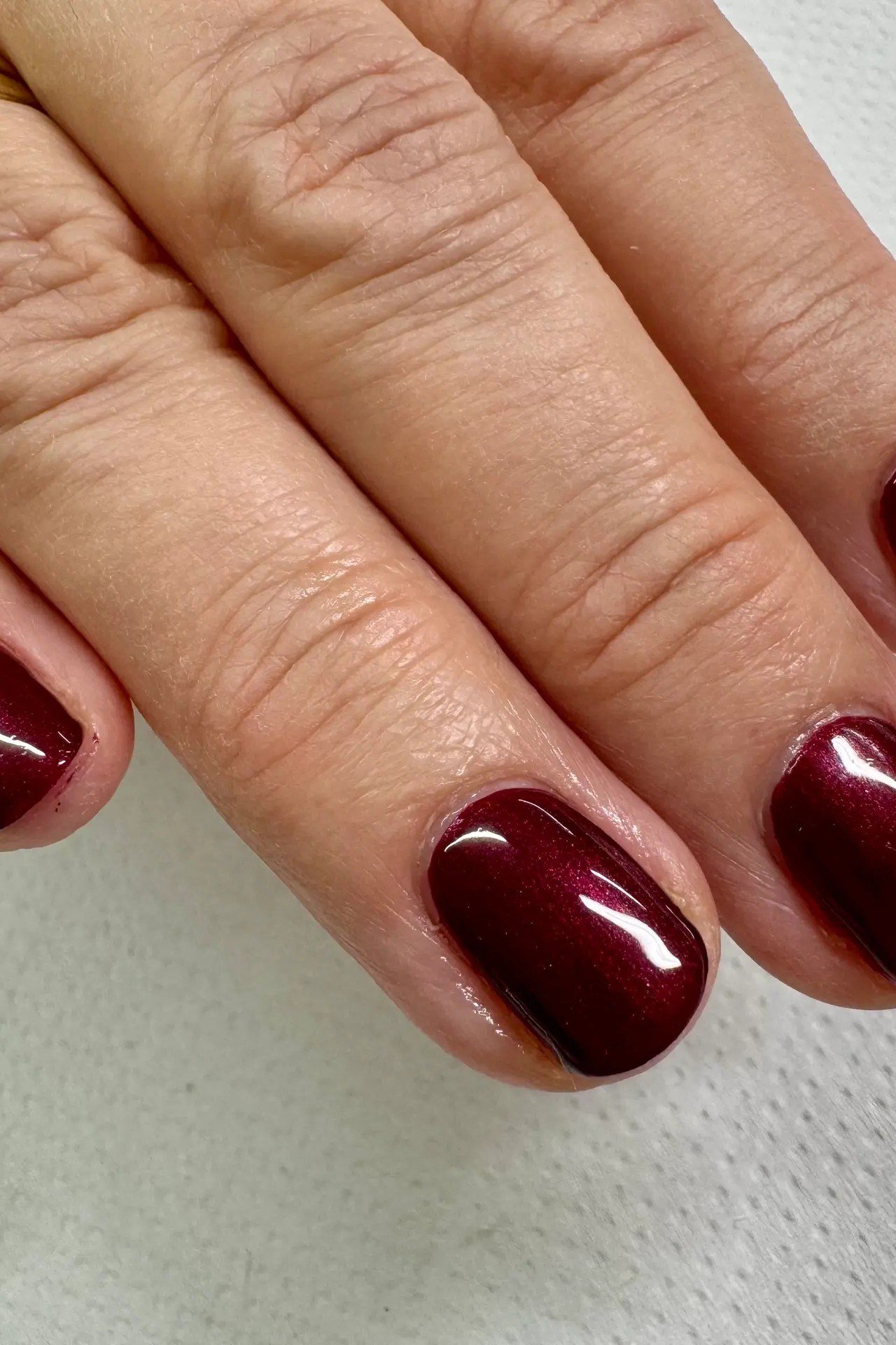 deep wine-burgundy glossy short oval nails, close view