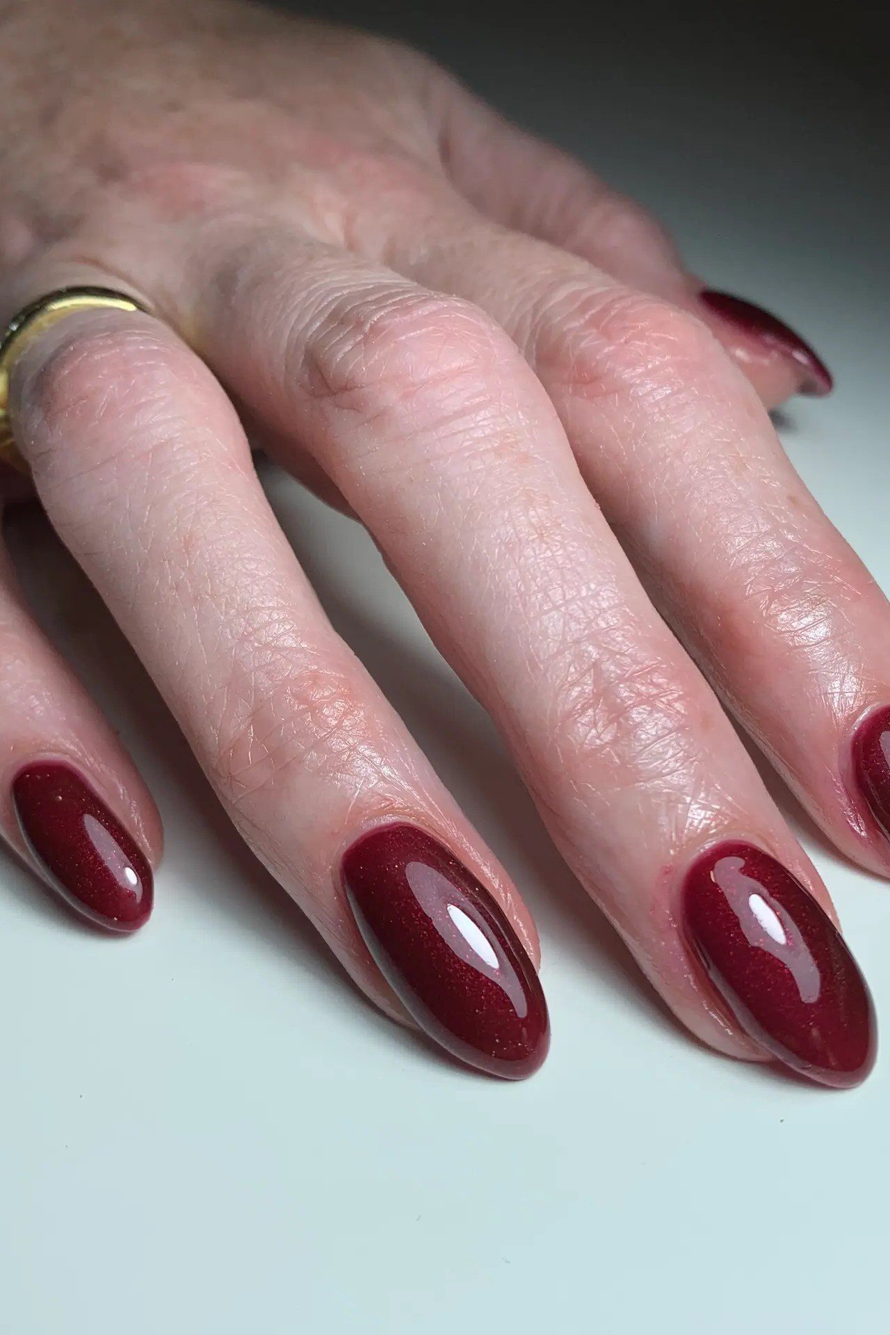 deep red glossy almond medium nails, relaxed hand