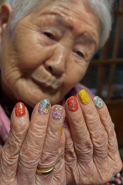 rainbow multi-color short nails, elderly woman holding hands near face