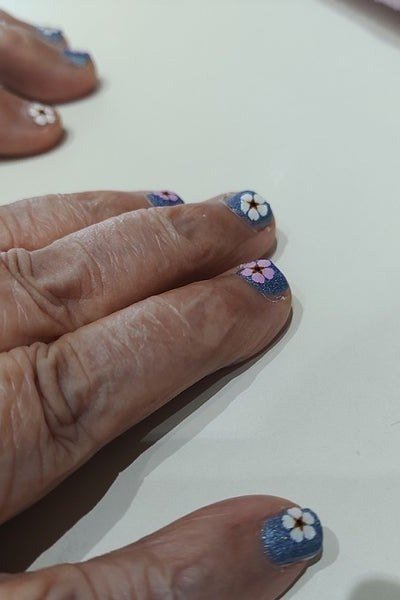 deep blue short nails with white daisy art on dark mature hands