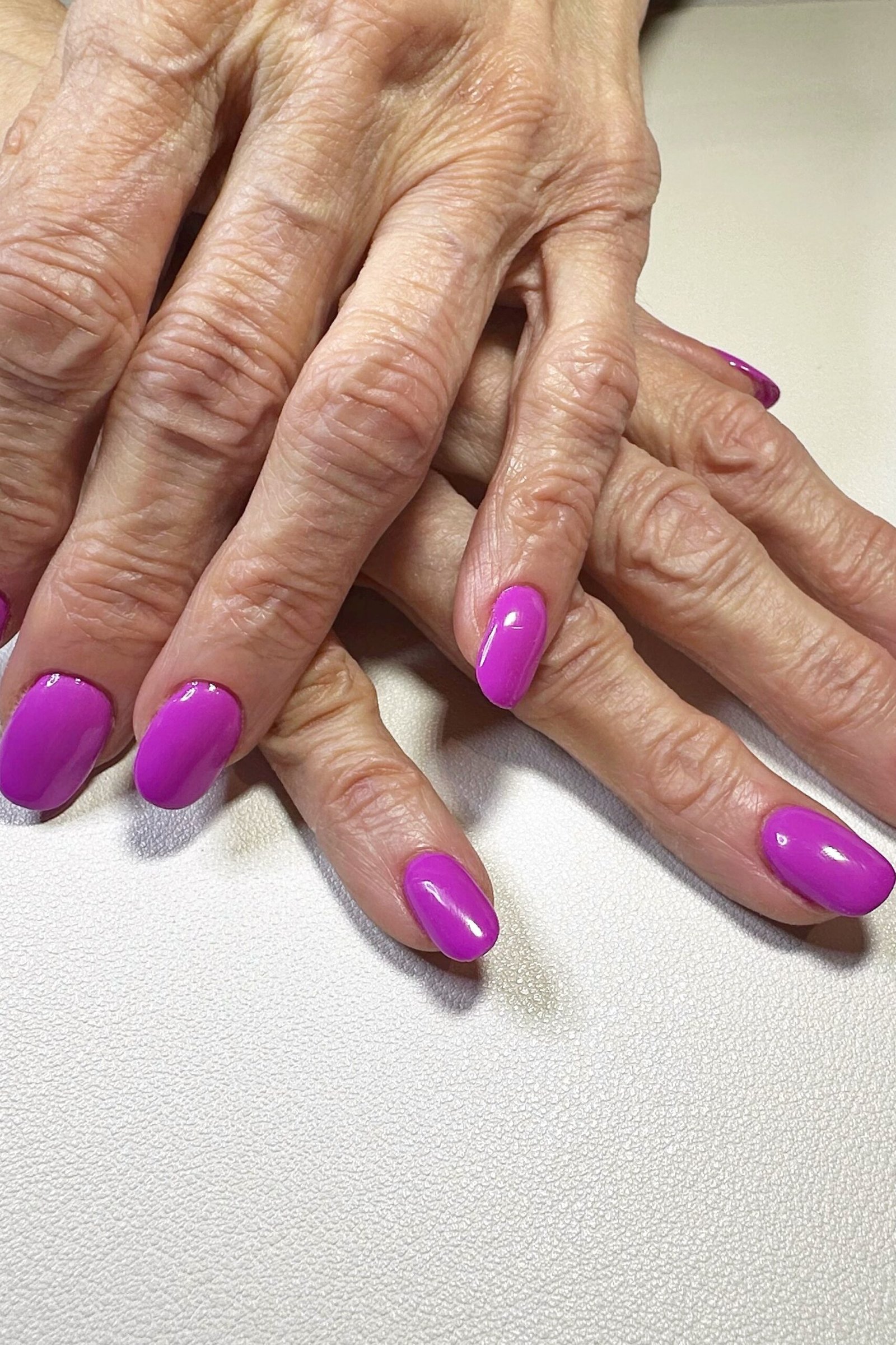 neon purple glossy short nails on crossed hands