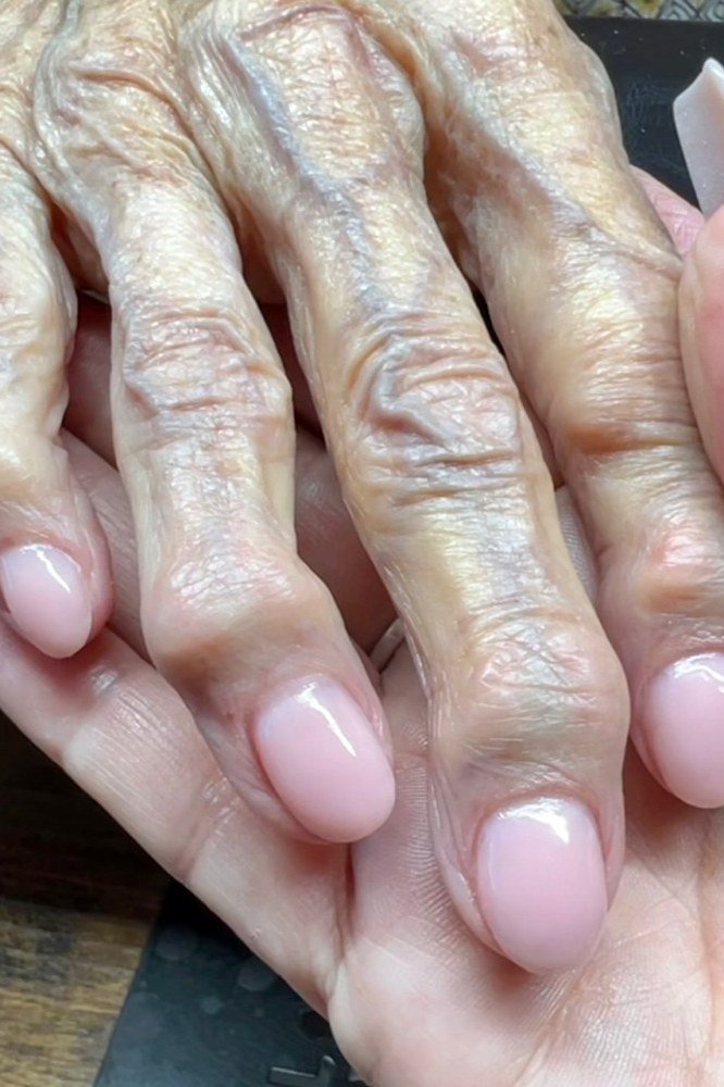 baby pink short nails with pearl accent, one hand over other