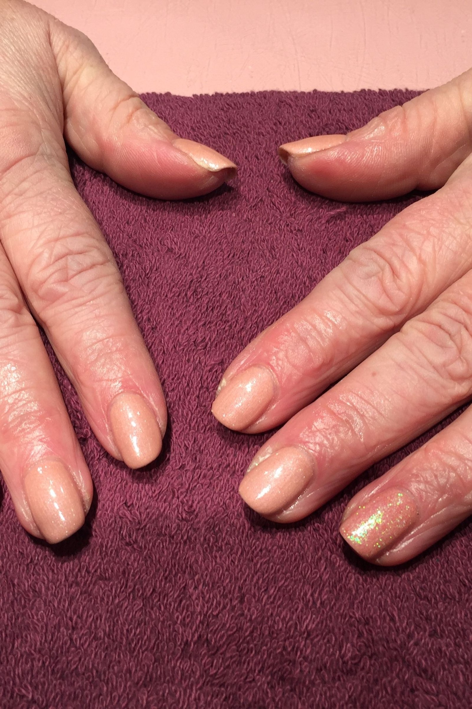 gold shimmer nude short nails on burgundy towel