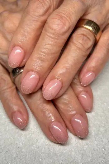 blush pink glossy medium nails on crossed hands with gold ring