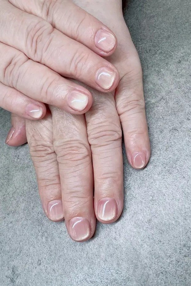 milky white-pink sheer short nails on crossed hands