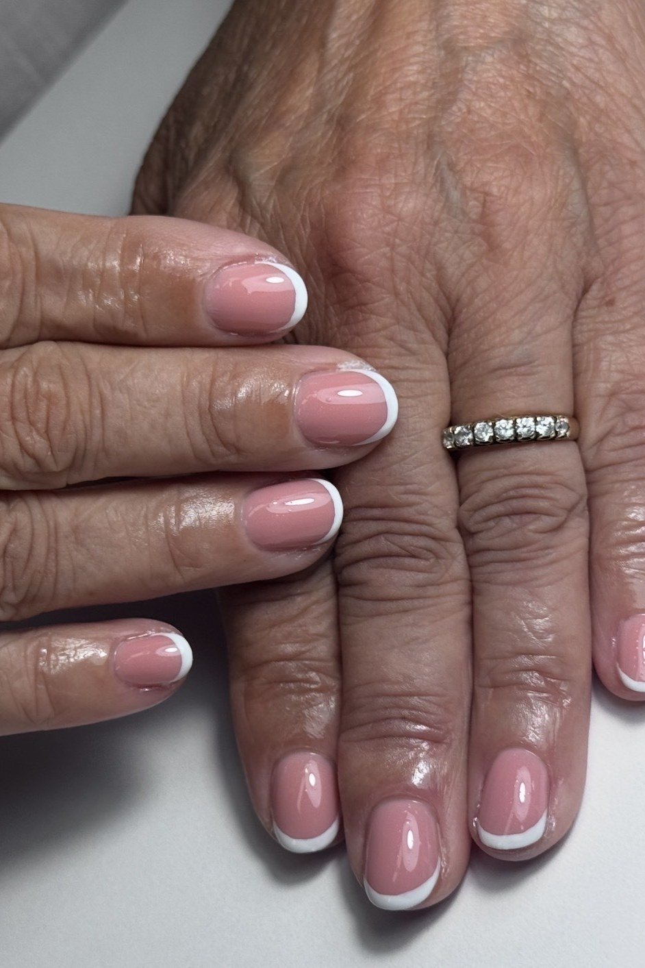 pink bases with white french tips on dark mature hands with diamond ring