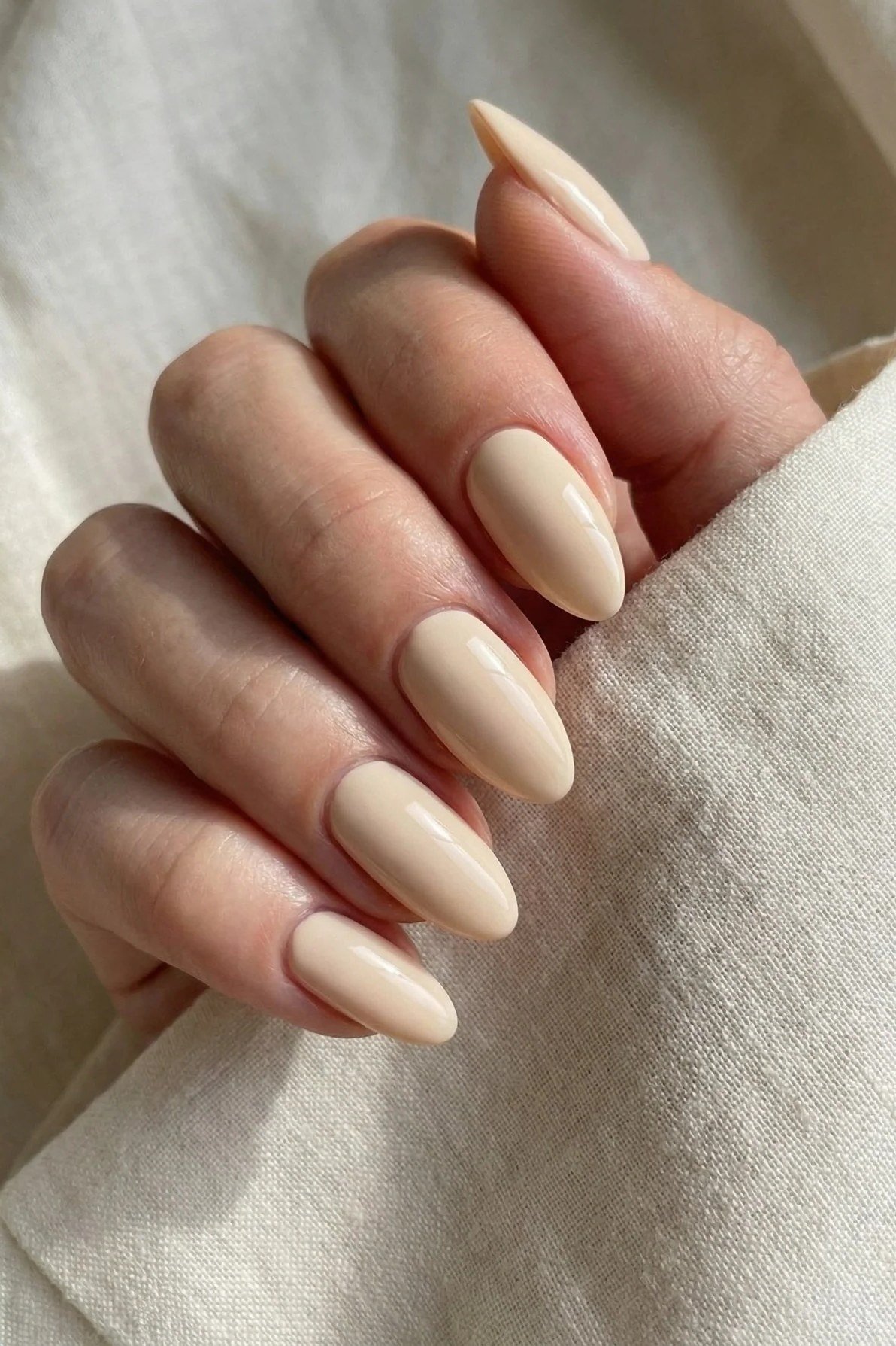 Creamy beige nude almond nails on ivory fabric - caramel nude nail idea for women over 50