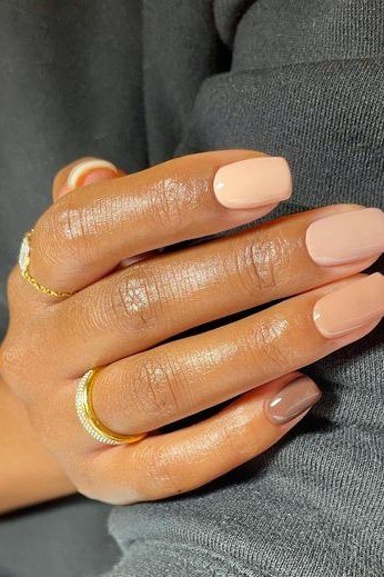 Warm nude squoval nails with gold rings on deep skin - caramel nude nail idea for women over 50