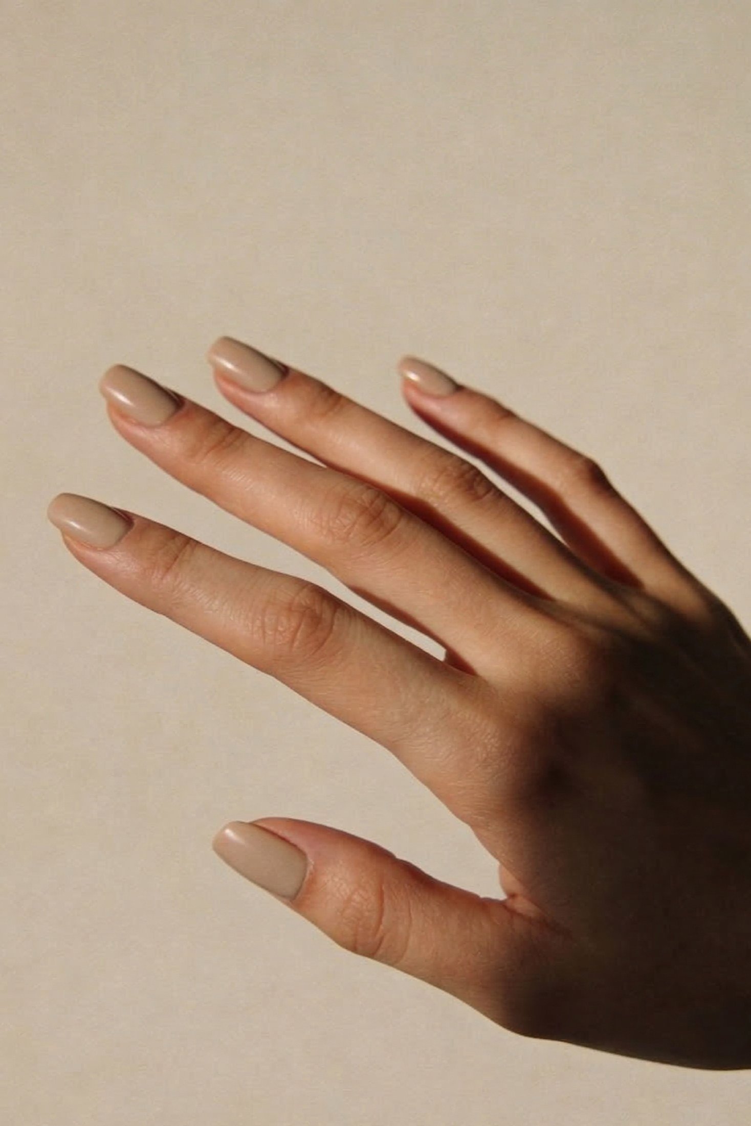 Caramel nude almond nails on an elegant extended hand - caramel nude nail idea for women over 50