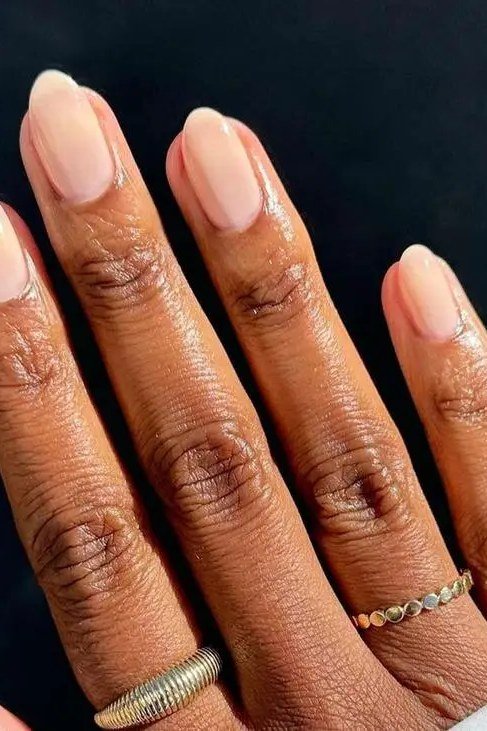 Soft nude squoval nails with rings on deep skin - caramel nude nail idea for women over 50