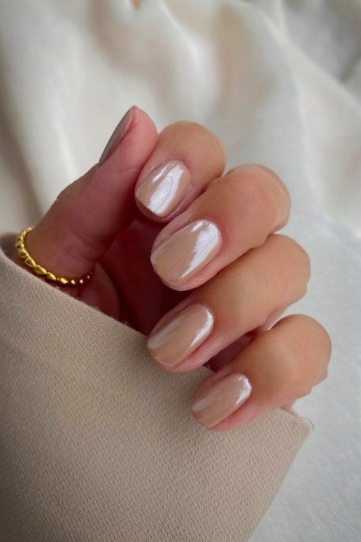 Pearly nude squoval nails with a gold bracelet - caramel nude nail idea for women over 50