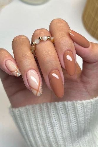 Caramel nails with white swirl accent and knit sleeve - caramel nude nail idea for women over 50