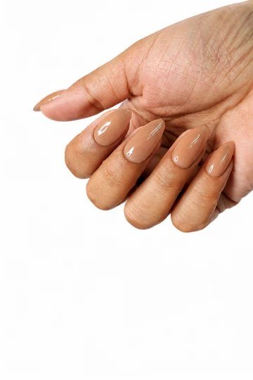 Clean nude almond nails on a white background - caramel nude nail idea for women over 50