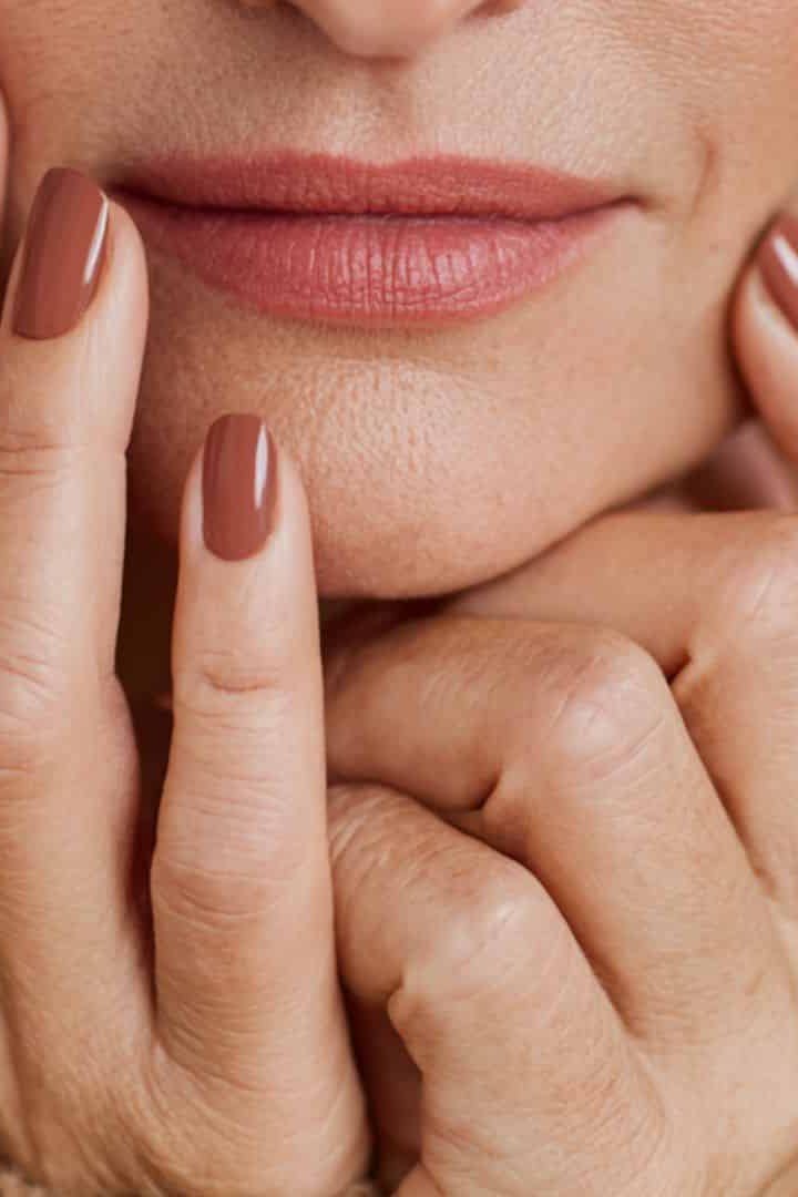 Terracotta caramel nails, face-framing hands of an older woman - caramel nude nail idea for women over 50