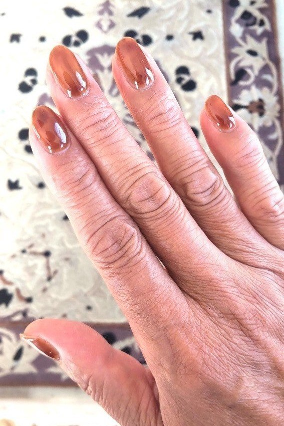 Sheer caramel nails on an aged hand - caramel nude nail idea for women over 50