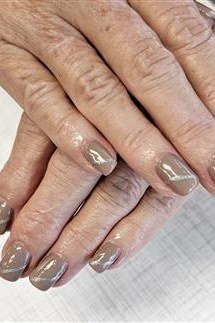 Taupe grey nude nails on elderly folded hands - caramel nude nail idea for women over 50