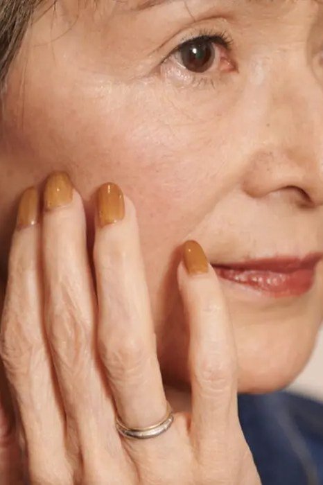 Caramel nails, face-framing hands of an older woman - caramel nude nail idea for women over 50
