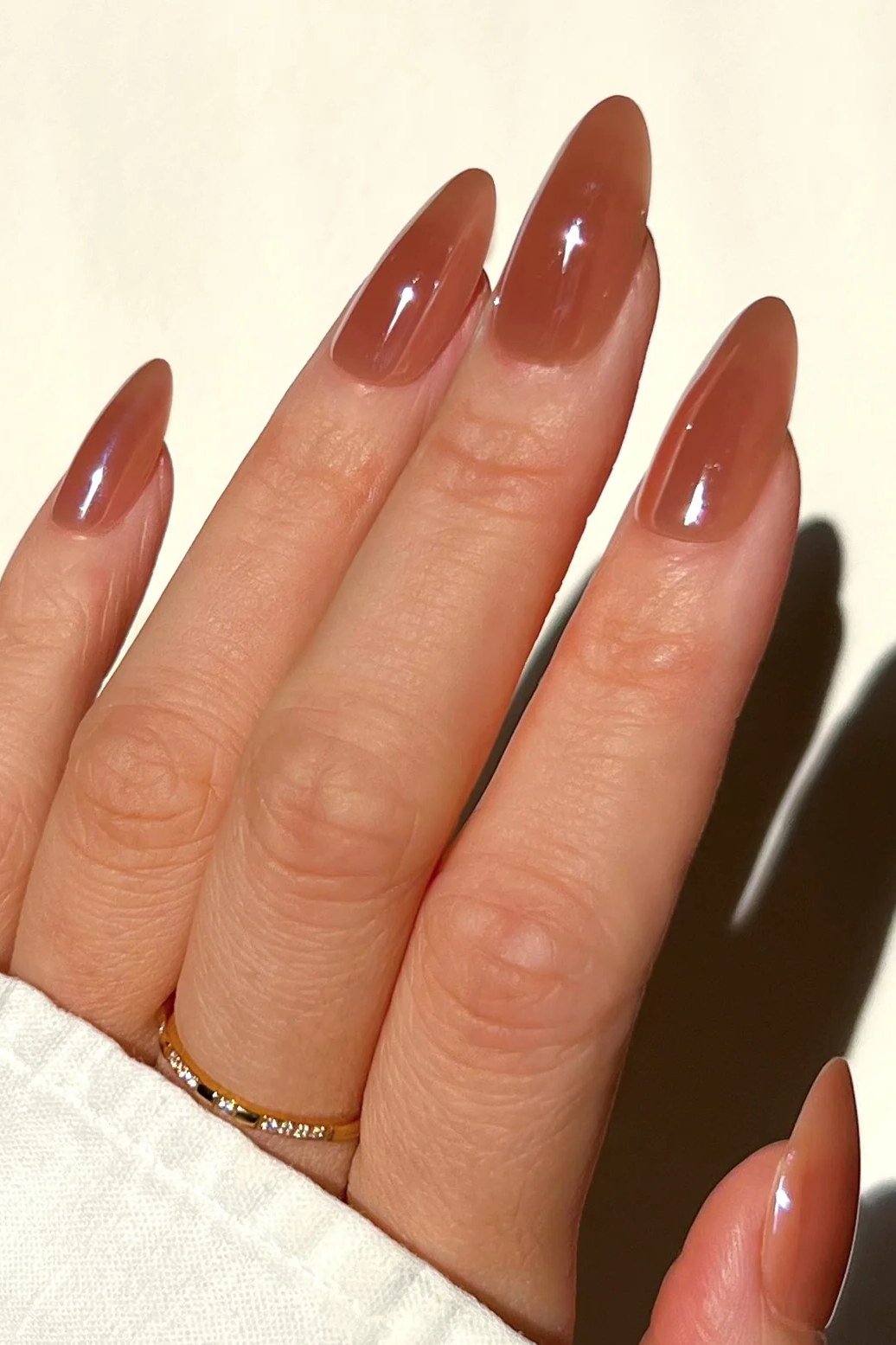 Glossy caramel almond nails in sunlight - caramel nude nail idea for women over 50
