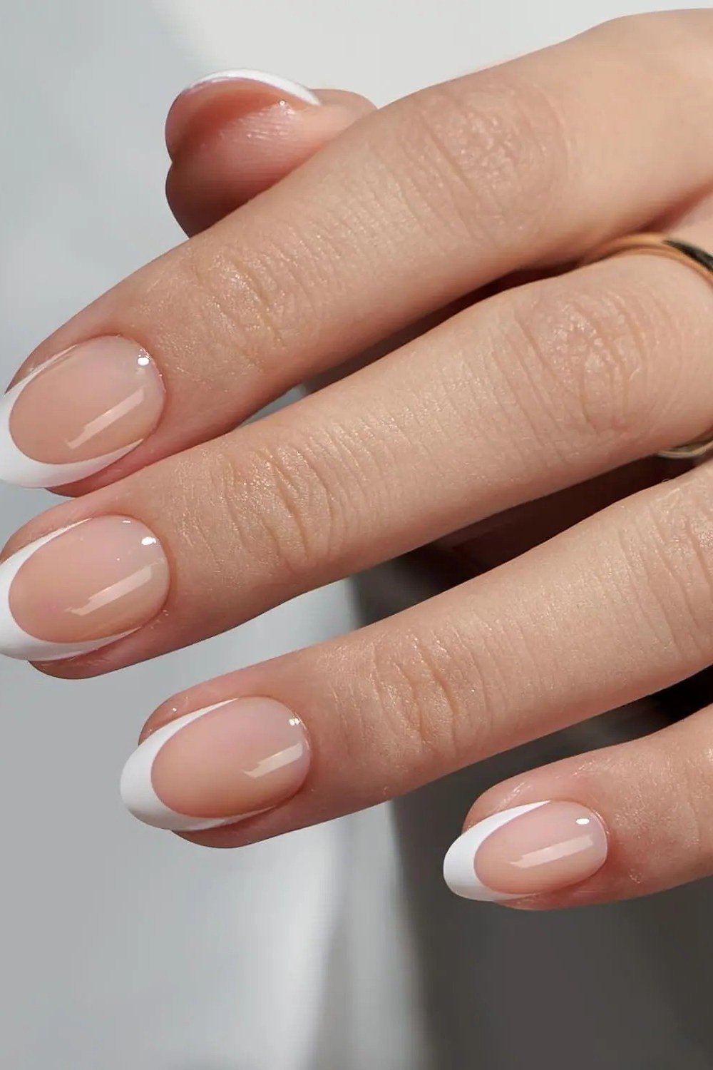 Nude almond french tip with gold ring - flattering nail idea for women over 50