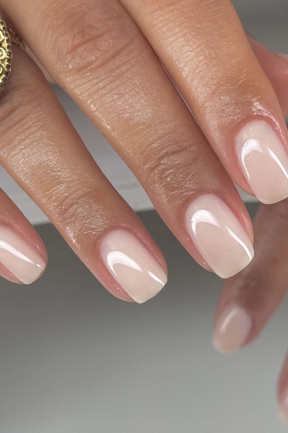 Glossy nude almond, gold ring - flattering nail idea for women over 50