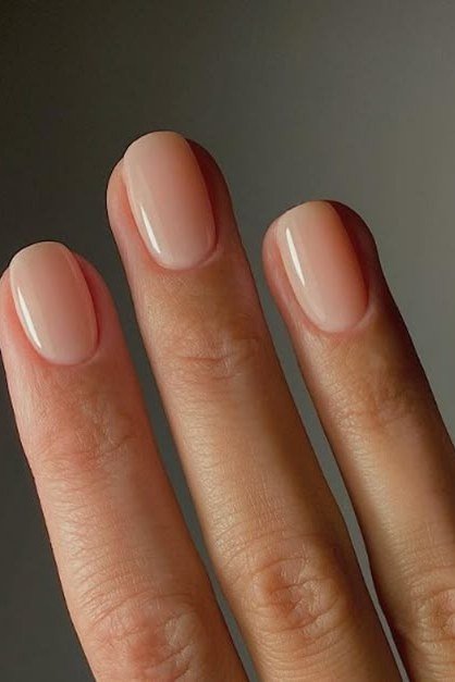Nude almond nails, dark background - flattering nail idea for women over 50