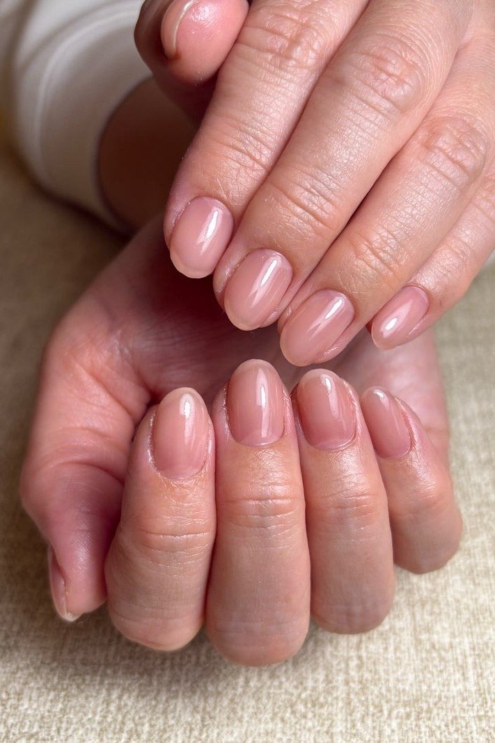 Pale pink short nails, folded hands - flattering nail idea for women over 50
