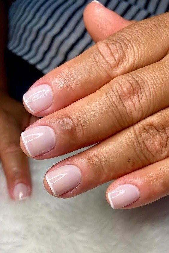 Pink french tip on brown skin hands - flattering nail idea for women over 50
