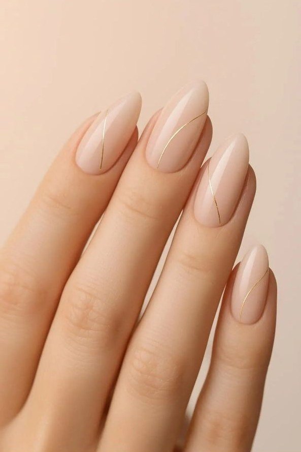 Long almond nude nails with gold line accents for women over 50