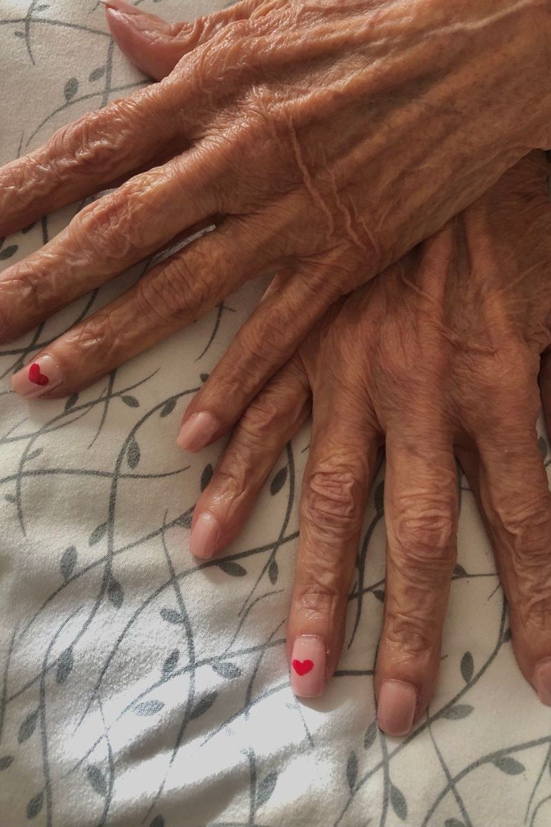 Tiny red heart art on sheer nude, old hands - nail art for women over 50
