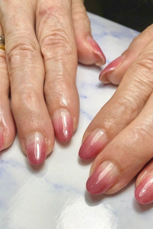 Pink ombre fade on almond nails, mature hands