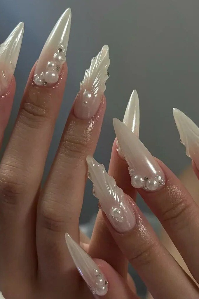 Long white stiletto nails with 3D shell and pearl embellishments