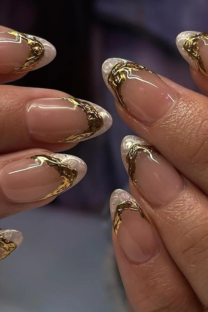Nude almond nails with ornate gold foil tips