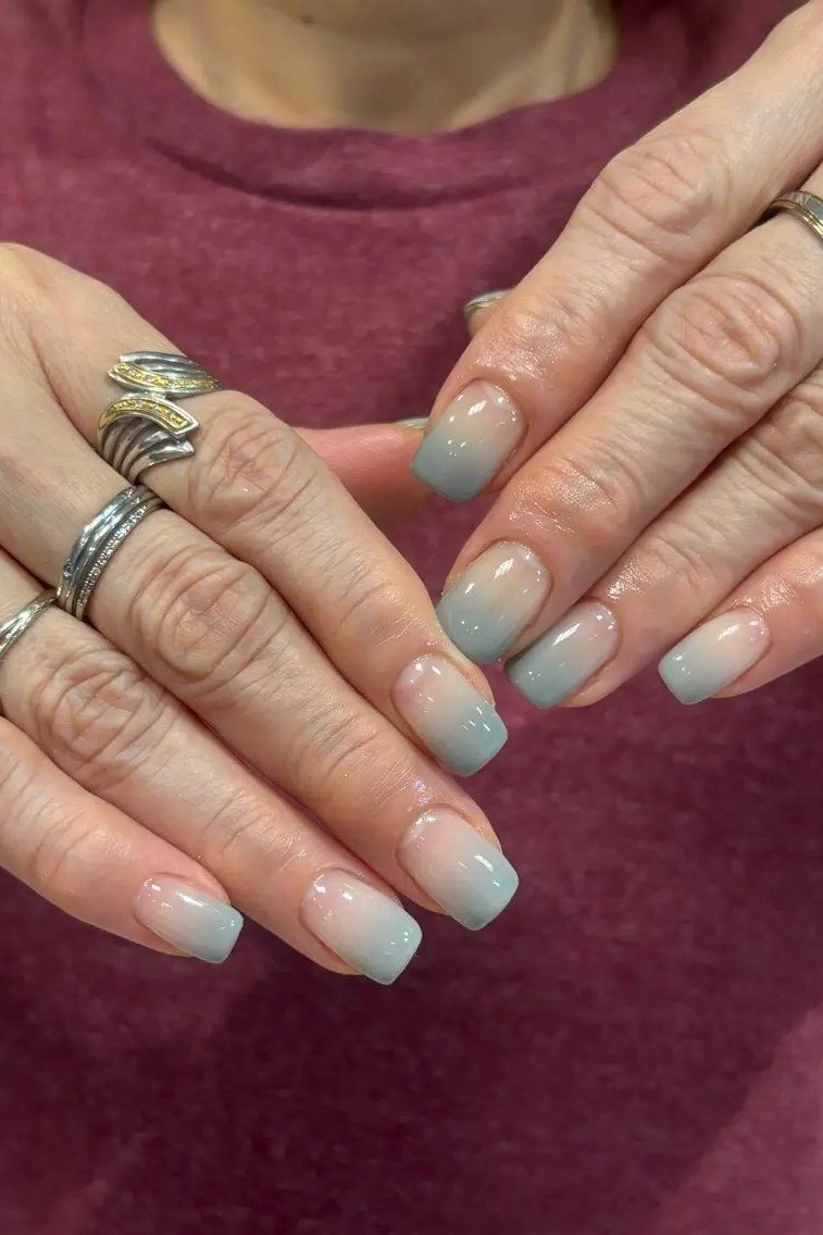Nude square nails with teal-blue tips, older hands with rings