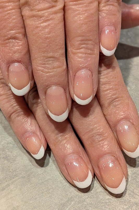 Crisp white French tips on longer nails for women over 50