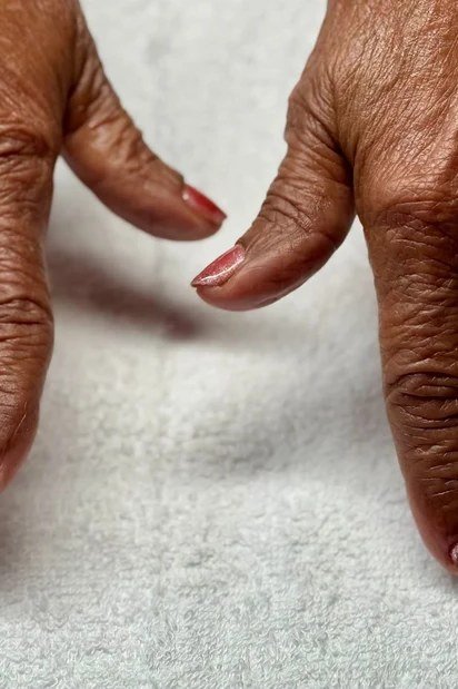 True red nail polish on deep skin tone hands for older women