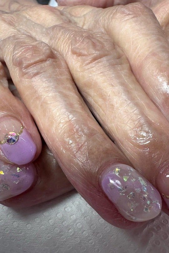 Lavender jelly nails with butterfly art on older hands - jelly nail idea for women over 60