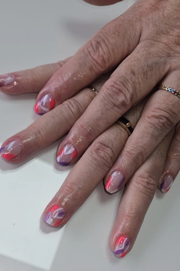 Sheer pink jelly nails with tiny art on older hands - jelly nail idea for women over 60