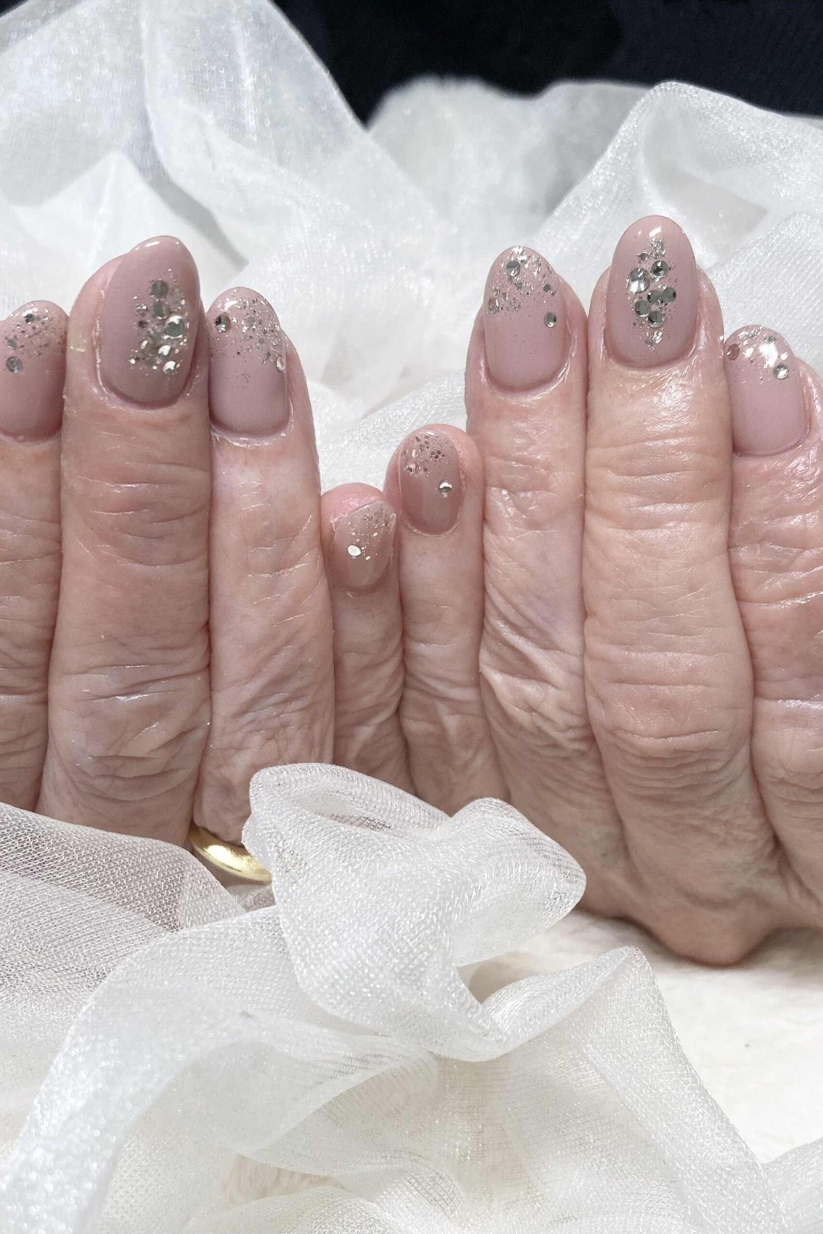 Hands with glittery mauve polish on clear base for women over 60 - simple clear nail idea 21