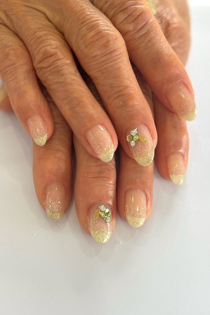 Hands with gold glitter tips on sheer base for women over 60 - simple clear nail idea 23