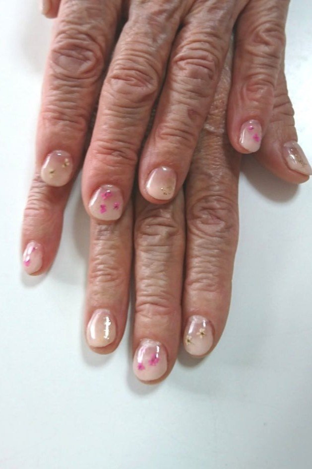 Hand with tiny heart-dot accents on sheer pink for women over 60 - simple clear nail idea 24